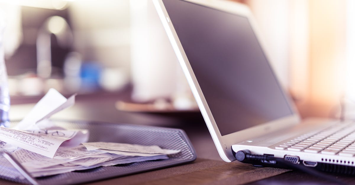 Mesa com computador, curriculo e boletos para organizar dividas durante desemprego