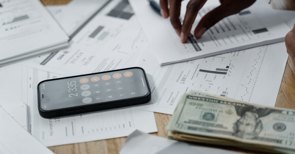Documentos financeiros, celular e calculadora usados para conferir valor e origem de uma negativacao